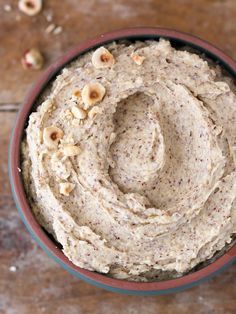 a bowl filled with hummus and nuts on top of a wooden table