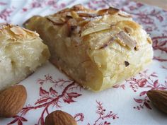 two pieces of dessert sitting on top of a red and white plate with almonds