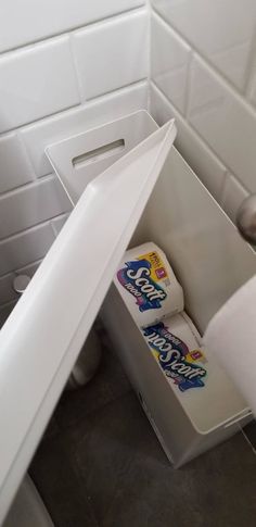 a roll of toilet paper is in the corner of a white box with its lid open