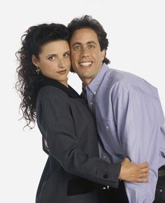 a man and woman hugging each other in front of a white background with one holding his arm around the other's shoulder