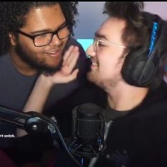 two men with headphones are talking to each other in front of a microphone and recording equipment