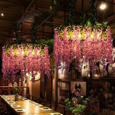 the dining room is decorated with pink flowers and greenery hanging from the chandelier