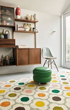 a green chair sitting on top of a rug in front of a wall mounted shelf