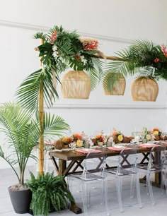 a dining room table set up with palm leaves and flowers