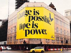 a yellow car is parked in front of a building with a large advertisement on it