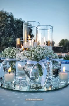 an arrangement of flowers and candles on a glass tray