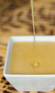 a small white bowl filled with liquid on top of a wooden table