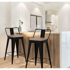 two black bar stools in front of a counter with a mirror and vase on it