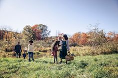 three people are standing in the grass with their suitcases and one person is carrying something