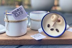 two coffee mugs are sitting on a wooden tray with some tags attached to them