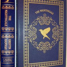 two blue books with gold trimmings on the covers and one has a bird