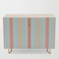 a striped cabinet with gold legs and pink, blue, yellow and green stripes on it