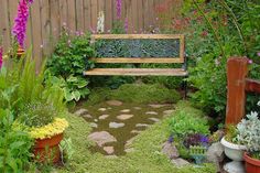 a wooden bench sitting in the middle of a garden filled with lots of plants and flowers