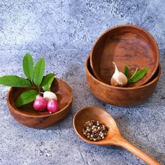 three wooden bowls filled with different types of vegetables and herbs on top of a table