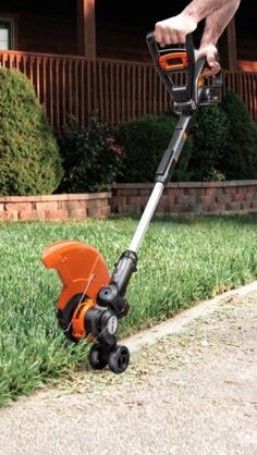 a man is trimming the grass with a lawnmower