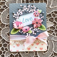 a close up of a card on a doily with hearts and flowers in the background