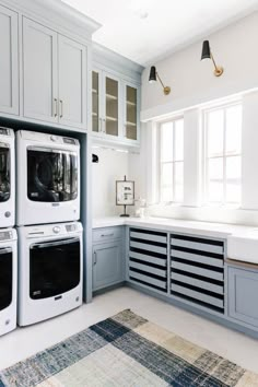 a white kitchen with blue cabinets and washer and dryer combos in it