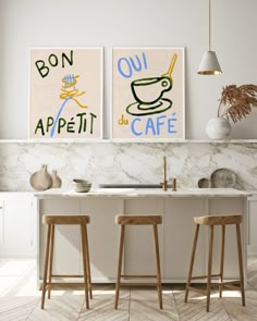 two posters on the wall above a kitchen sink with stools in front of them