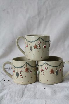 three coffee mugs are stacked on top of each other, decorated with christmas decorations