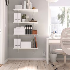 a white desk and chair in a room with bookshelves on the wall next to a window