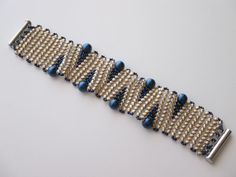 a close up of a bracelet on a white surface with blue beads and silver clasp