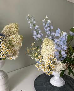 two white vases filled with different types of flowers