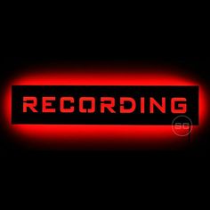 a red recording sign with the word recording lit up in it's dark room