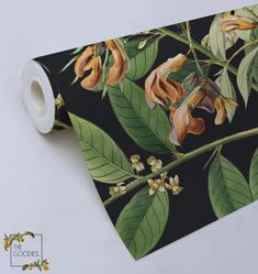 a close up of a tie with flowers and leaves on black background, next to a white wall