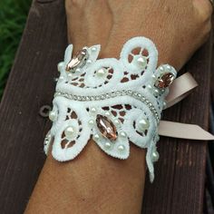 a woman's arm wearing a white lace bracelet with pearls