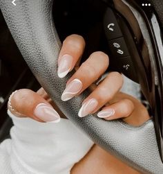 a woman's hand holding onto the steering wheel of a car with white nails