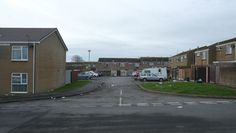 an empty street with cars parked on the side and houses in the backgrouds