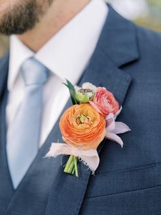 a man wearing a blue suit and tie with an orange flower on his lapel