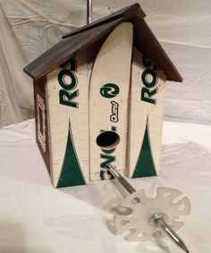 a birdhouse made out of skis and snowboards on a white sheeted surface