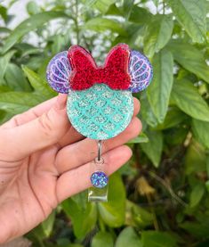 a hand holding up a mickey mouse pin with red, white and blue glitter on it