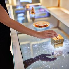 a woman's hand reaching for a box on a glass display table in a store