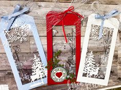 three tags with snowflakes on them hanging from a wooden wall