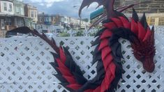 a red and black dragon wreath sitting on top of a white fence next to buildings