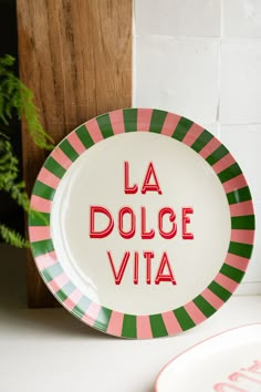 a plate with the words la dolce vita written in red and green on it