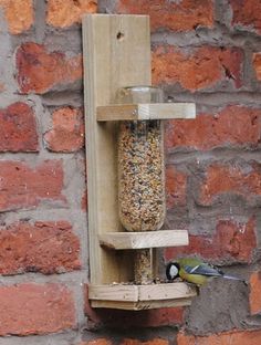 a bird feeder hanging from the side of a brick wall