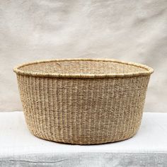 a large woven basket sitting on top of a white cloth covered tablecloth next to a wall