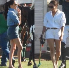 two women in short shorts and white shirts are walking on the grass with horses behind them