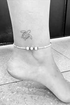 a small tattoo on the ankle of a woman's foot, with a turtle