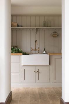 an open kitchen with white cabinets and wood flooring, along with a sink in the center