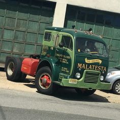 a green and red truck parked in front of a building