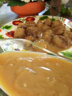 a plate with meatballs and gravy on it next to a flower pot