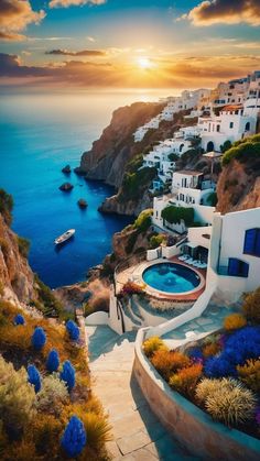 the sun is setting over an ocean with white houses and blue flowers in front of it