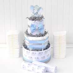 a three tiered baby shower cake with an elephant on top and blue ribbon around the edges