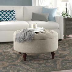 a living room with a white couch and blue pillows on the floor, along with a coffee table