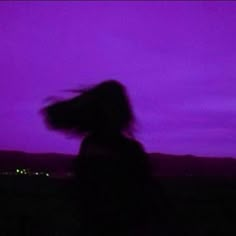 a blurry image of a person with long hair in front of a purple sky