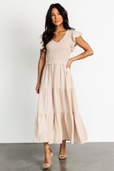 Our Afton Smocked Tiered Dress in Sand is a new staple piece for your closet. With flowy material and stretchy smocking, the Afton doesn't sacrifice comfort for style. Snag it now! Feminine Smocked Dress With Flutter Sleeve, Beige Ruched V-neck Maxi Dress, Chic Beige Smocked Dress With Smocked Bodice, Chic Beige Smocked Dress For Brunch, Feminine Beige Maxi Dress With Smocked Bodice, Beige Feminine Maxi Dress With Smocked Bodice, Chic Beige Smocked Dress With Smocked Back, Chic V-neck Smocked Dress With Ruffle Hem, Feminine Beige Midi Dress With Smocked Bodice